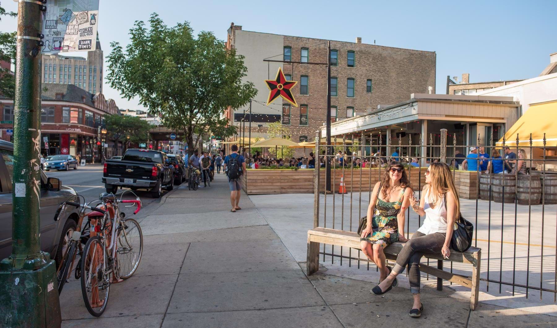 a couple of women sitting on a bench in a city