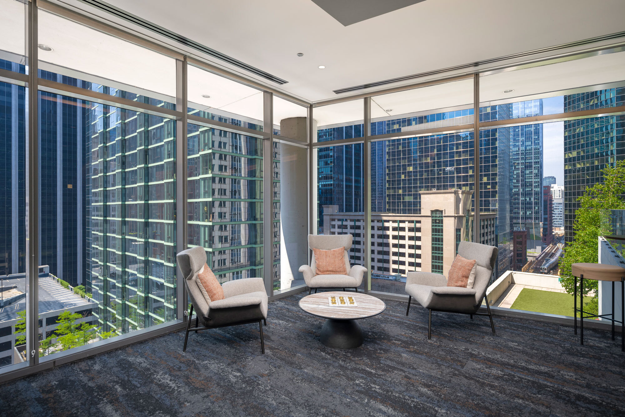 Chicago apartment at Lake & Wells with floor to ceiling windows and chairs and a coffee table.